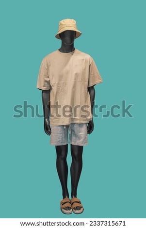Full length image of a male display mannequin wearing beige t-shirt gray shorts and hat isolated on a green background  Royalty-Free Stock Photo #2337315671