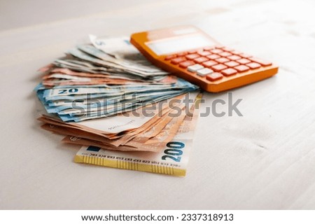 Pile of various value Euro banknotes money spread on the table with an orange calculator on the cash. Conceptual image of savings, budget and costs. Royalty-Free Stock Photo #2337318913
