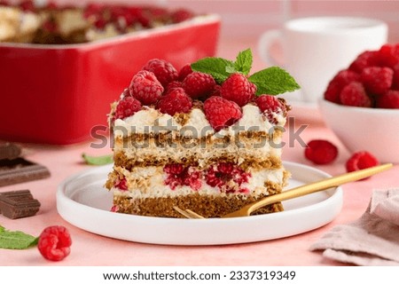 A piece of tiramisu with raspberries on a white plate on the table. Traditional Italian dessert. Selective focus Royalty-Free Stock Photo #2337319349