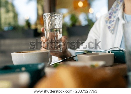 Woman drinking water at the dining table. Water balance in the body concept