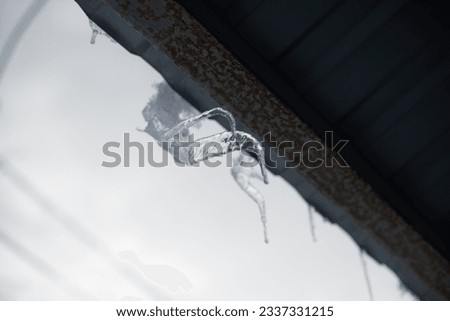 Ice on goat of roof. Icicles on roof. Ice on house. Melting snow.