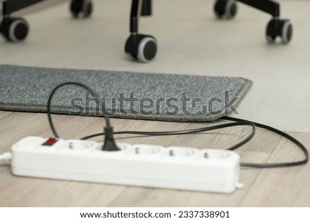 Electric warming mat near office chair for heating white working on the computer. Electric mat on the floor Royalty-Free Stock Photo #2337338901