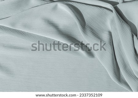 Neutral pale blue fabric texture with folds and natural sunlight shadows. Aesthetic summer wedding bohemian background