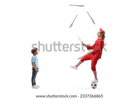 Boy watching a man in a red suit standing on a football and juggling isolated on white background