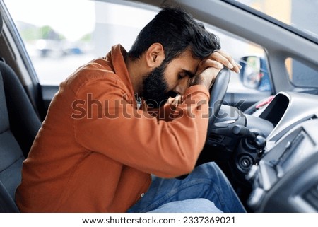 Unhappy Middle Eastern Driver Man Resting Head On Wheel Sitting In Car, Napping Exhausted During Trip. Desperate Guy Having Problems With His Automobile. Vehicle Crash, Transport Ownership Issue Royalty-Free Stock Photo #2337369021