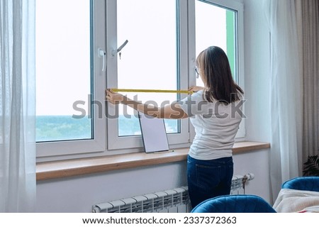 Woman measuring window with tape measure, tailoring service Royalty-Free Stock Photo #2337372363