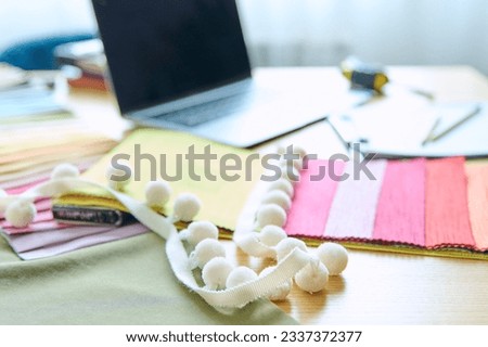 Workplace of designer, decorator, samples of fabrics and accessories recording notebook on table