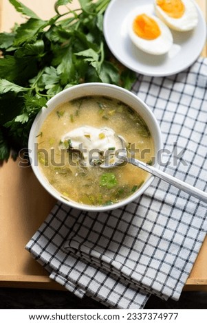 A bowl of green summer soup borscht with sorrel and boiled eggs with a spoonful of natural yogurt on a wooden background. Diet vegetable soup. Royalty-Free Stock Photo #2337374977