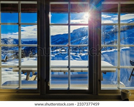 View through the window from cozy wooden cabin to snowy mountains during winter. Ski center accommodation.  Royalty-Free Stock Photo #2337377459