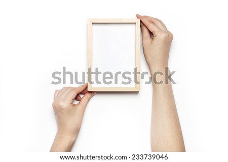 A female hands hold(grip) a wooden photo(picture) frame isolated white, top view at the studio. 