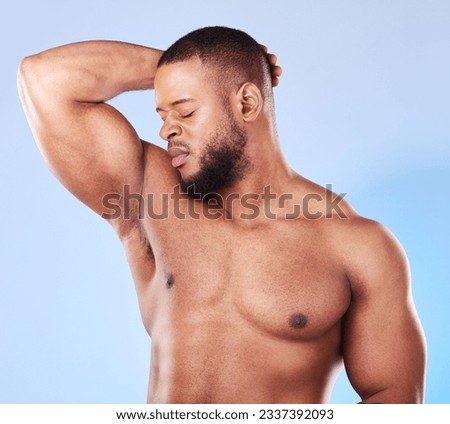 Man, armpit and bad smell in studio for body odor, deodorant and cleaning for skincare. Black male model, underarm and stink from sweating, dirty hygiene and personal grooming on blue background Royalty-Free Stock Photo #2337392093