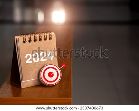 Happy new year 2024 banner background. 3d target icon with 2024 numbers year on brown small desk calendar cover standing on table edge with sunlight and copy space. Business goal and success concepts.