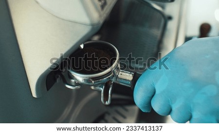 Barista's glove hand using stainless steel coffee portafilter Royalty-Free Stock Photo #2337413137