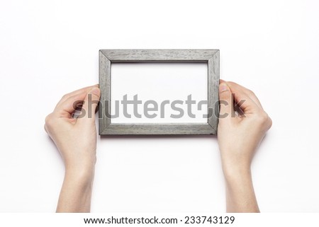 A female hand hold a wood photo(picture) frame isolated white, top view at the studio.