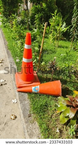 Traffic cones were placed in the grass next to the building when the rain had stopped.