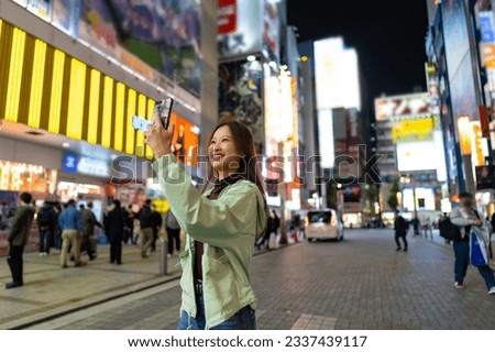 Happy Asian woman using mobile phone taking selfie during shopping at Tokyo city, Japan. Attractive girl enjoy outdoor lifestyle travel city street with using wireless technology on holiday vacation.