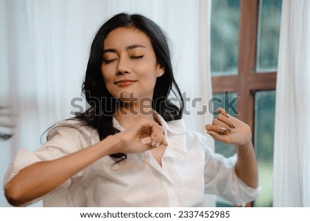 Hotel relaxation on lazy day with Asian woman waking up from good sleep on bed in weekend morning resting in comfort bedroom celebrating having happy work-life quality balance lifestyle