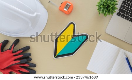 A hard hat, a laptop and a Japanese beginner's mark. An image of an inexperienced engineer. Royalty-Free Stock Photo #2337461689