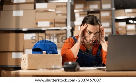 Stressed working at storehouse. Upset depressed worried disappointed female worker working in industry factory warehouse site in export. Copy space Royalty-Free Stock Photo #2337467807