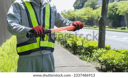 A security guard man with a red stick.