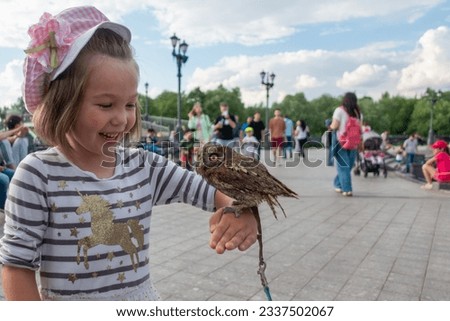 Girl holding small owl while standing in park against sky Royalty-Free Stock Photo #2337502067
