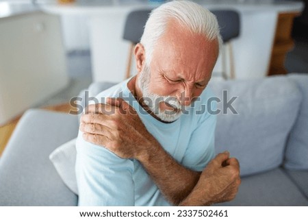Senior elderly man touching his shoulder, suffering from shoulder pain, sciatica, sedentary lifestyle concept. shoulder health problems. Healthcare, insurance Royalty-Free Stock Photo #2337502461