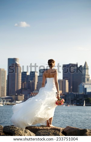 Young beautiful girl stands on the rocks over Boston downtown background