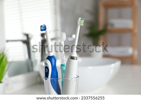 Electric toothbrushes in glass holder indoors, closeup