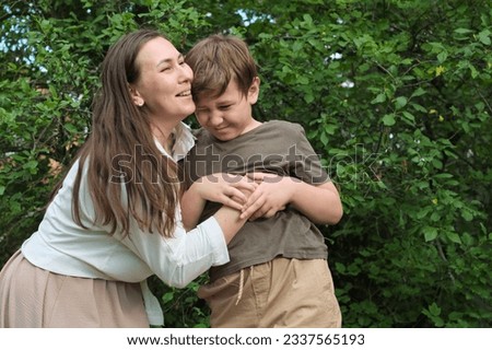 Mother and pre-teen son caught in a candid moment of laughter during a park photoshoot, demonstrating the allure of spontaneous photography Royalty-Free Stock Photo #2337565193