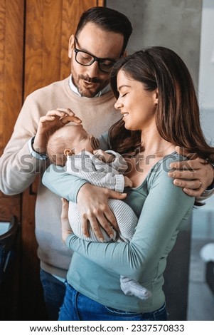 Peaceful young married couple enjoying being family, parents, holding new born baby in arms Royalty-Free Stock Photo #2337570833