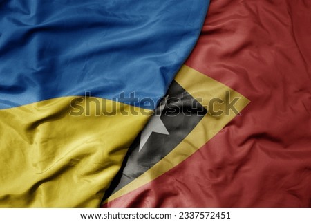 big waving national colorful flag of ukraine and national flag of east timor . macro