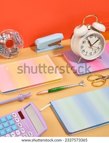 Creative workspace with school supplies. Calculator, vintage alarm clock, scissors and colorful notebooks.