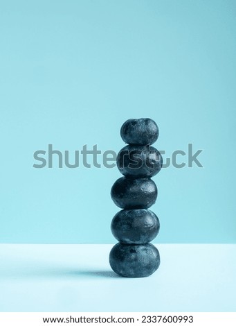 Pile of black berries against a 2 colour blue background