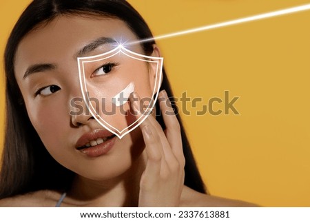 Beautiful woman applying sunscreen onto face against golden background, space for text. Illustration of shield symbolizing sun protection Royalty-Free Stock Photo #2337613881