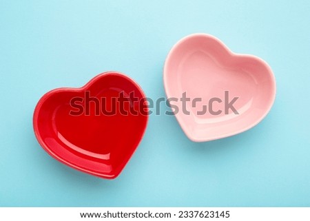 Red and pink heart shaped bowls on blue background. Top view Royalty-Free Stock Photo #2337623145