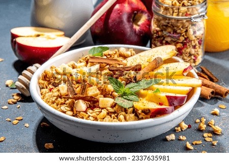 Healthy autumn breakfast granola. Apple pie granola with muesli, cinnamon spices, apples slices, honey and nuts, on black stone background copy space