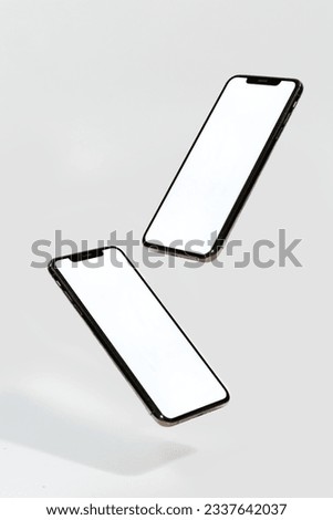 Two phones floating above the ground on white background Royalty-Free Stock Photo #2337642037