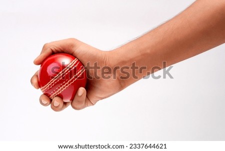 A Male Hand Holding A Red Leather Cricket Ball Isolated On White Background