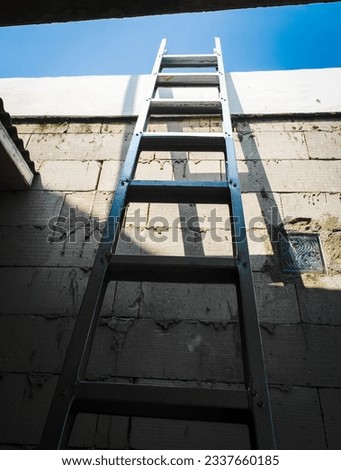 the ladder leans against the wall of the house