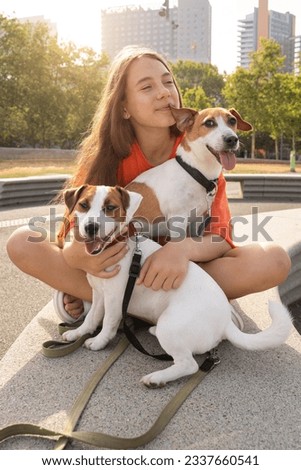 Hugging cuddling with with adorable Jack Russell terrier dogs. Summer holidays mood. Bright orange color clothes. Love and trust pet owner looking at camera. Happy summer holidays in big city