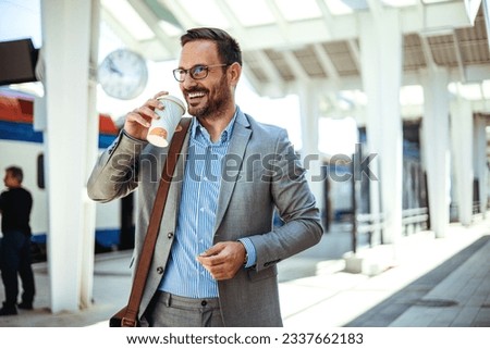 Businessman holding a disposable coffee cup at the train station platform. A man in a train station commuting to work. Businessman with coffee cup. Business person is waiting for train  Royalty-Free Stock Photo #2337662183