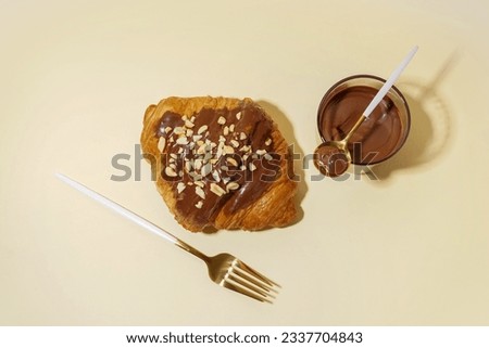 Sweet croissant and glass of chocolate on beige background