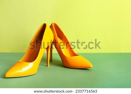 Pair of stylish high heeled shoes on green background Royalty-Free Stock Photo #2337716563