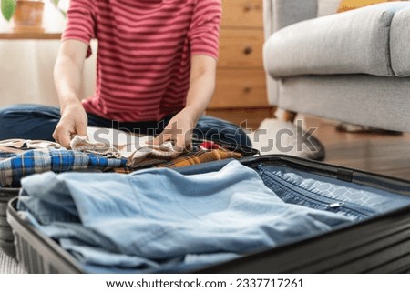 Preparing suitcase for summer vacation trip. Young woman checking accessories and stuff in luggage on the bed at home before travel. Royalty-Free Stock Photo #2337717261