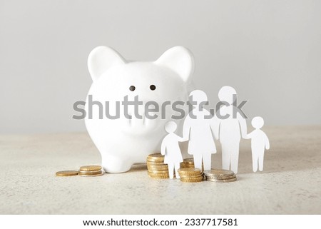Figures of family with piggy bank and coins on light table. Savings concept Royalty-Free Stock Photo #2337717581