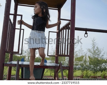 Jumping portrait image with smiling little brown haired girl. Concept happy and beauty kid with good healthy with blur background. Six year child wearing white and black in garden.