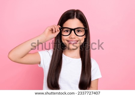 Photo portrait of pretty young child girl touch wear try eyeglasses dressed stylish white clothes isolated on pink color background