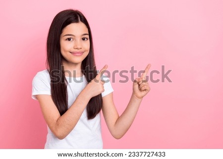 Photo portrait of adorable schoolkid female fingers point empty space promo dressed stylish white clothes isolated on pink color background