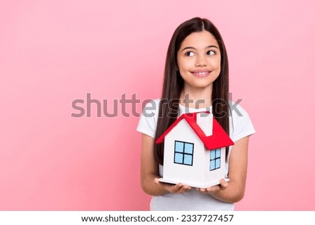 Photo portrait of pretty young child girl hold small house look empty space dressed stylish white clothes isolated on pink color background