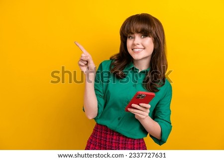 Photo of pretty shiny girl dressed green shirt chatting twitter telegram facebook pointing empty space isolated yellow color background